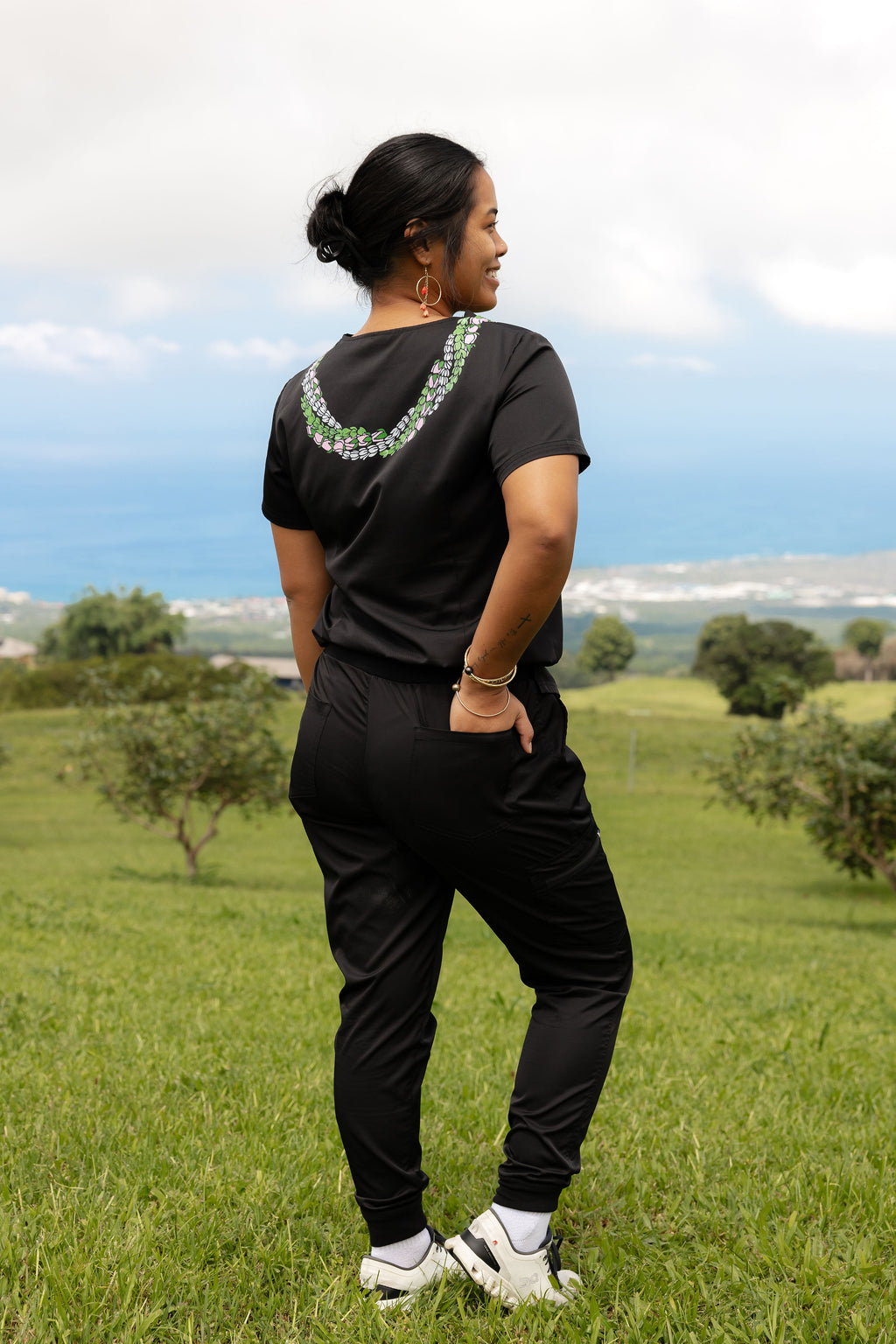 Back view of women’s black scrub set featuring Hawaii-inspired lei design