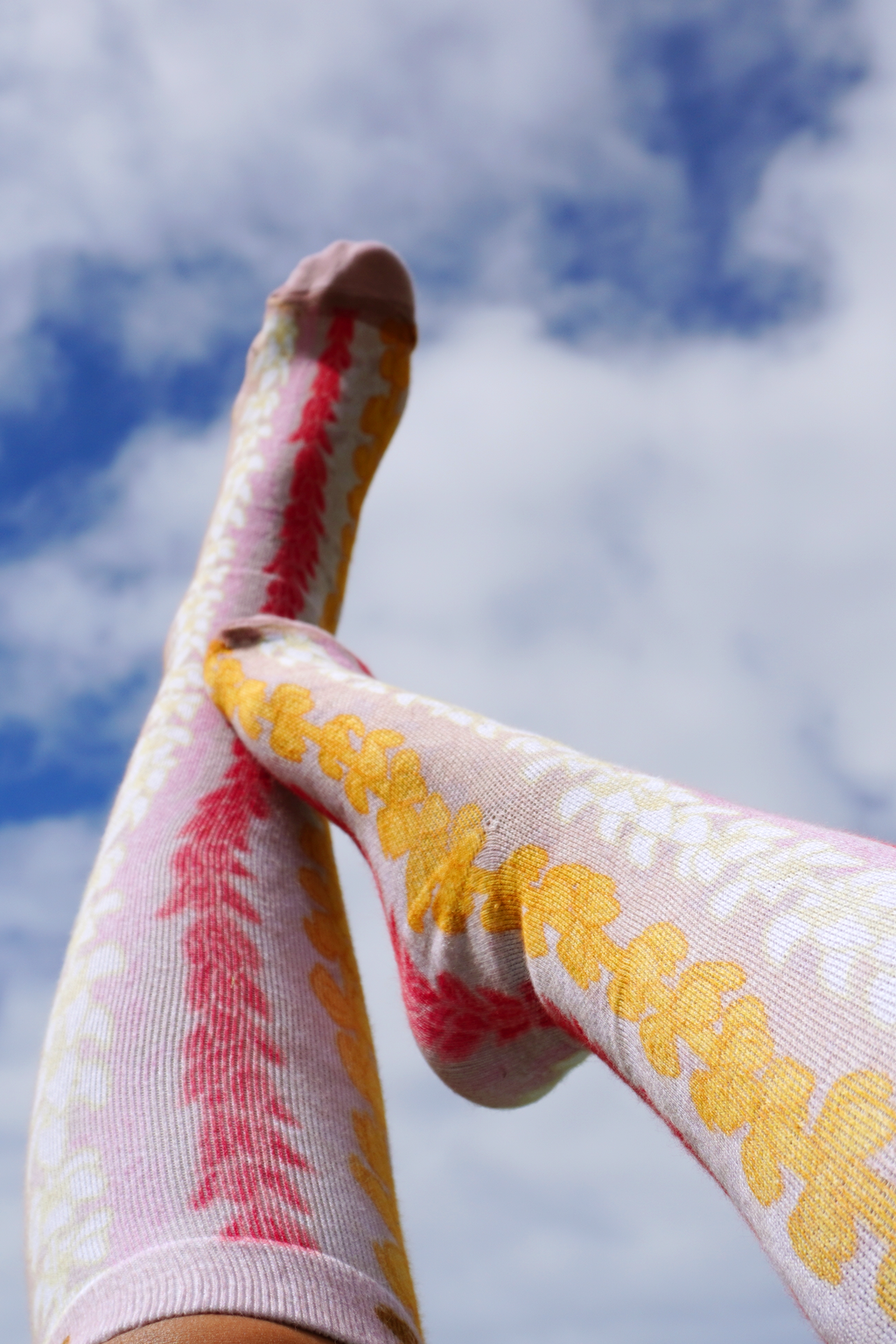 Colorful aloha print compression socks against bright blue sky backgrund